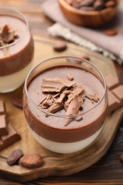 Photo of Delicious panna cotta with chocolate and cocoa beans on wooden table, closeup