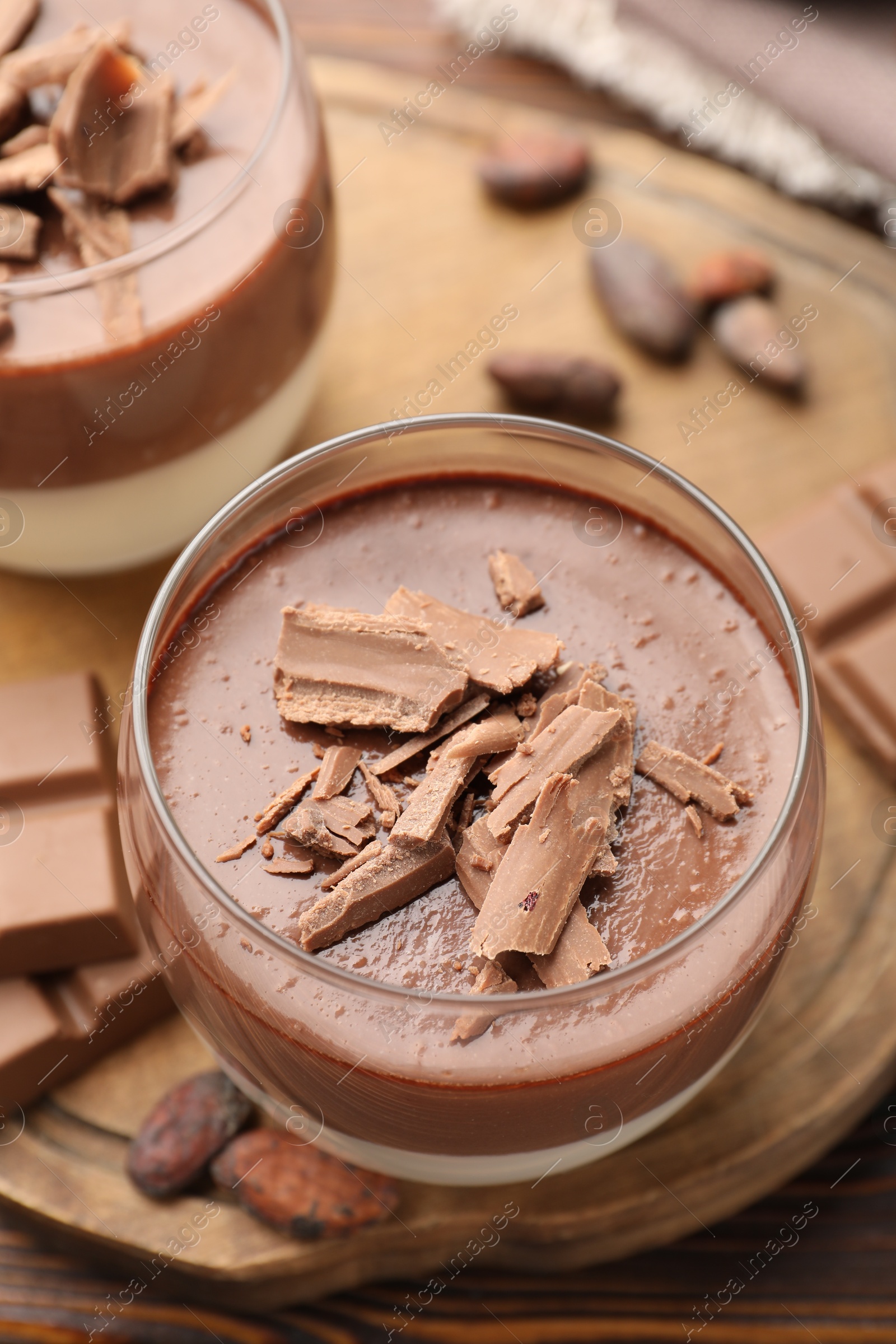 Photo of Delicious panna cotta with chocolate and cocoa beans on wooden table, closeup