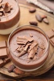 Photo of Delicious panna cotta with chocolate and cocoa beans on wooden table, closeup