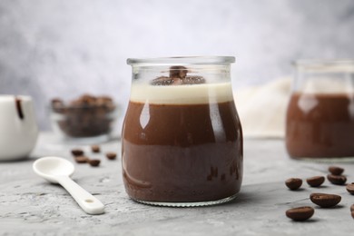 Photo of Delicious panna cotta and coffee beans on grey textured table, closeup