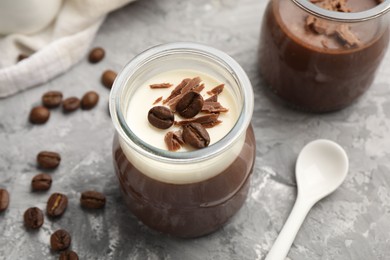 Photo of Delicious panna cotta with chocolate chunks and coffee beans on grey textured table, closeup
