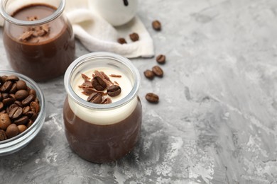 Photo of Delicious panna cotta with chocolate chunks and coffee beans on grey textured table. Space for text