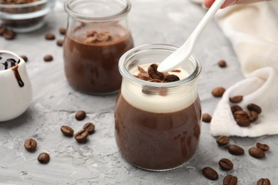 Photo of Woman eating delicious panna cotta at grey textured table, closeup