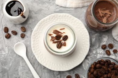 Photo of Delicious panna cotta with chocolate chunks and coffee beans served on grey textured table, flat lay