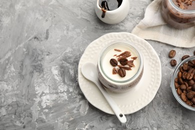 Photo of Delicious panna cotta with chocolate chunks and coffee beans served on grey textured table, above view. Space for text