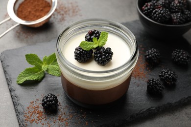 Photo of Tasty panna cotta with blackberries, mint and cocoa powder on grey table, closeup