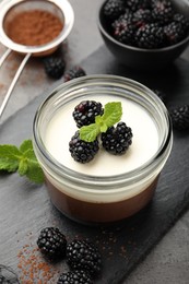 Photo of Tasty panna cotta with blackberries, mint and cocoa powder on grey table, closeup