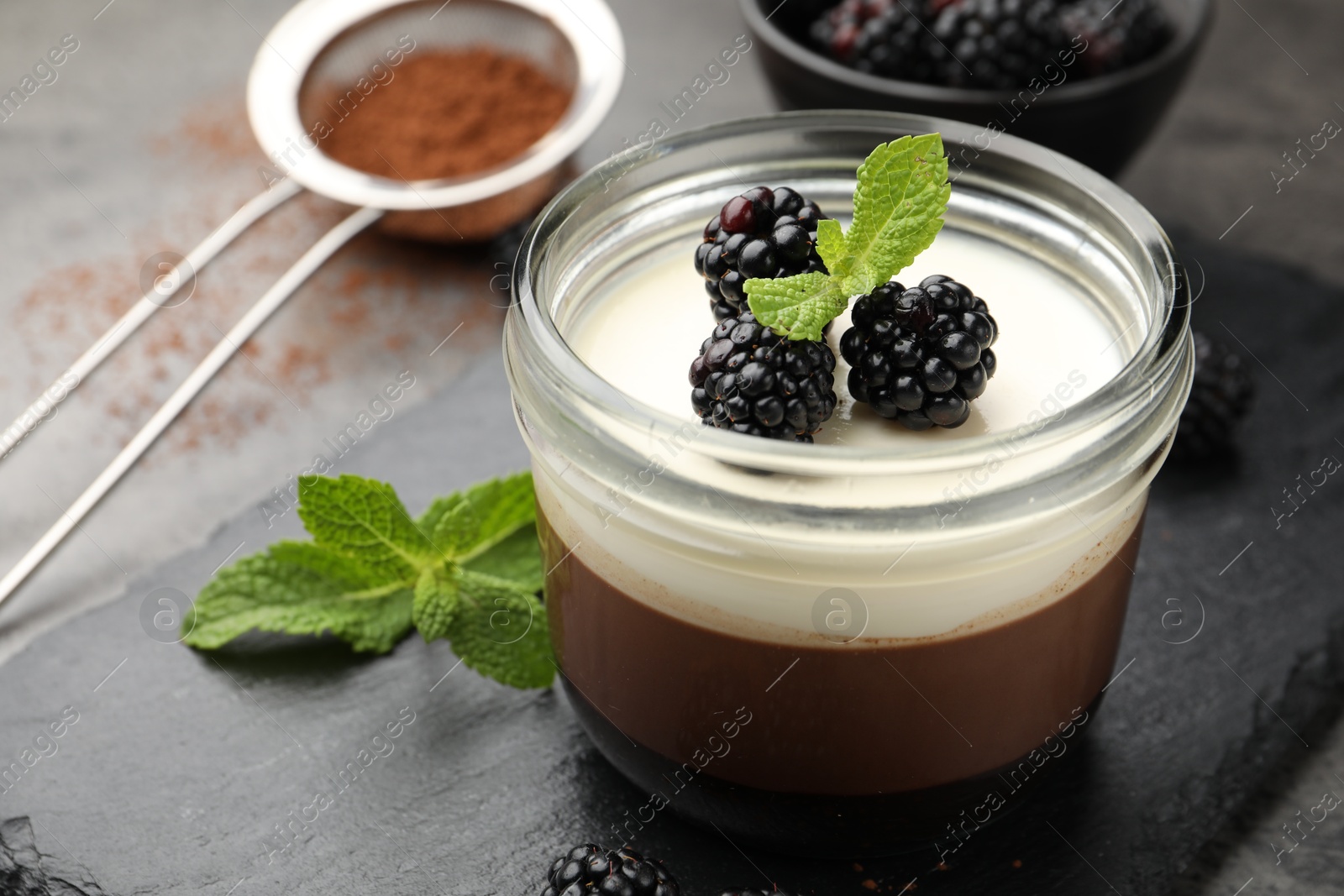 Tasty panna cotta with blackberries, mint and cocoa powder on grey table, closeup Photo of Tasty panna cotta with blackberries, mint and cocoa powder on grey table, closeup