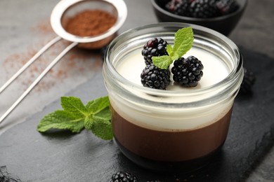 Photo of Tasty panna cotta with blackberries, mint and cocoa powder on grey table, closeup