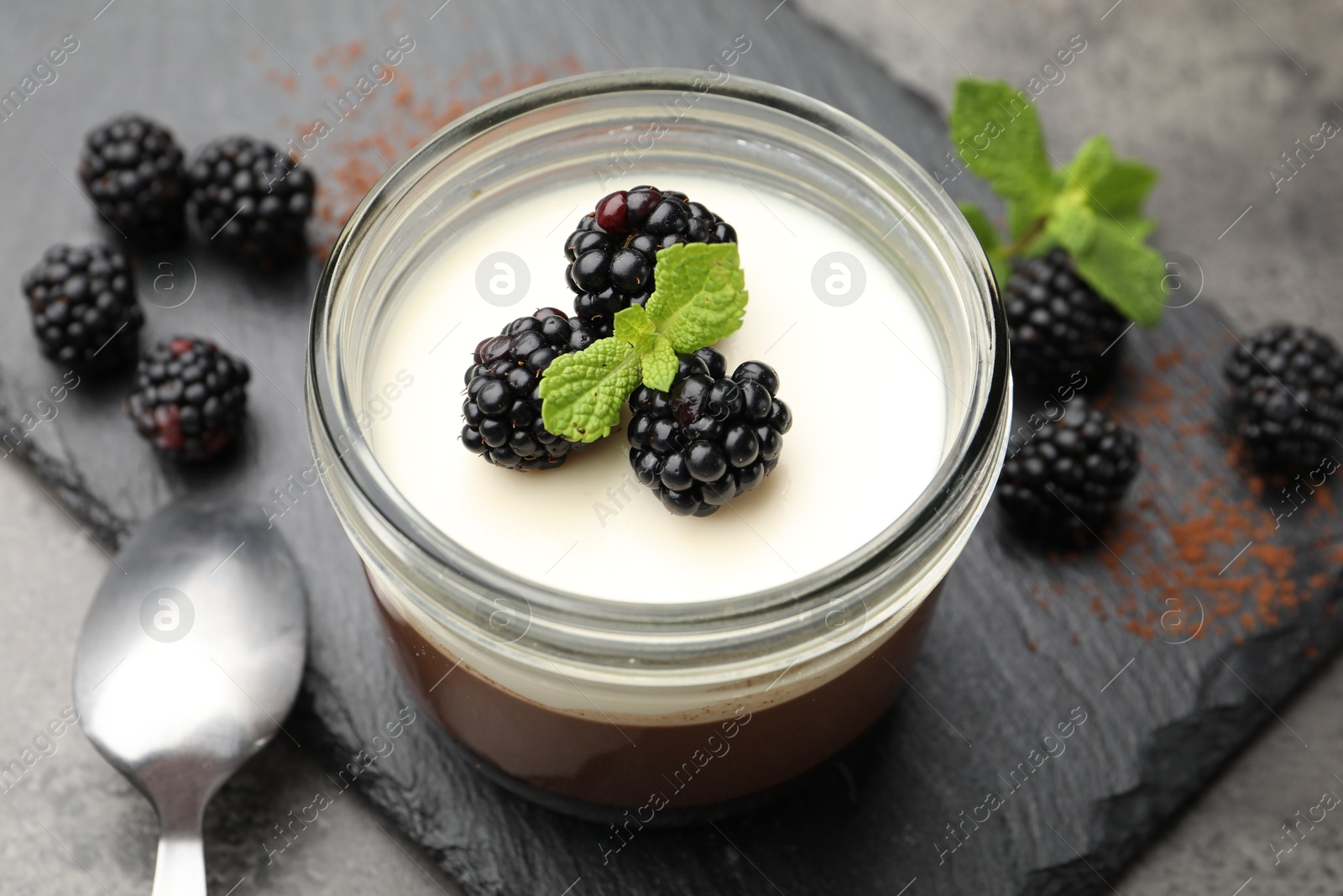 Tasty panna cotta with blackberries, mint and cocoa powder on grey table, closeup Photo of Tasty panna cotta with blackberries, mint and cocoa powder on grey table, closeup