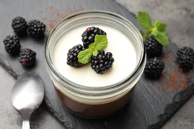 Photo of Tasty panna cotta with blackberries, mint and cocoa powder on grey table, closeup