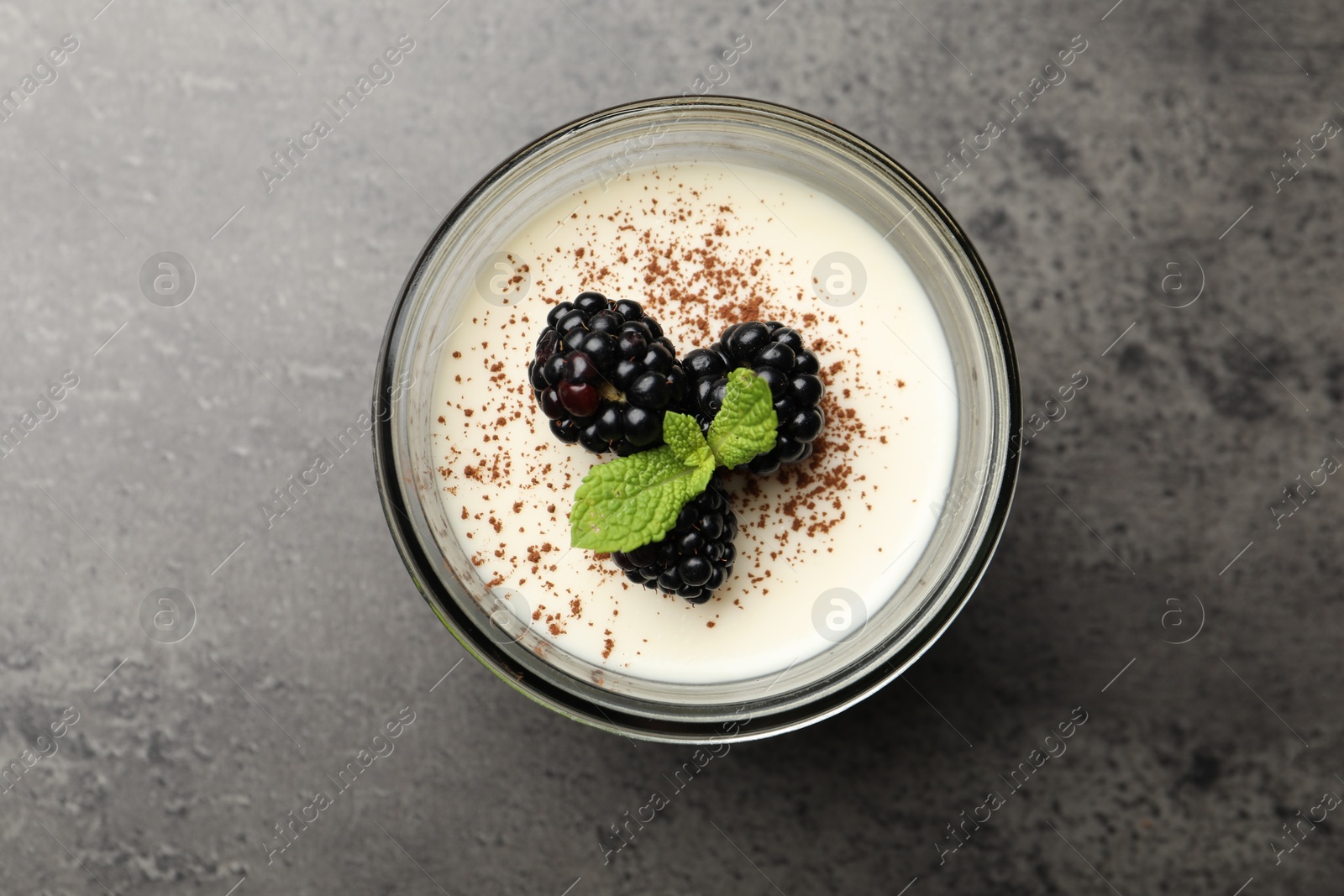 Tasty panna cotta with blackberries, mint and cocoa powder in jar on grey table, top view Photo of Tasty panna cotta with blackberries, mint and cocoa powder in jar on grey table, top view