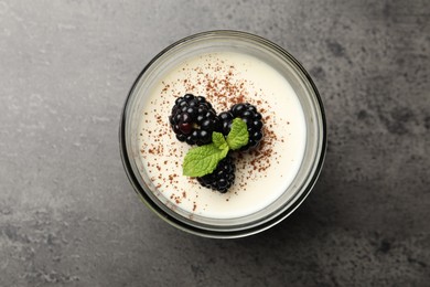 Photo of Tasty panna cotta with blackberries, mint and cocoa powder in jar on grey table, top view