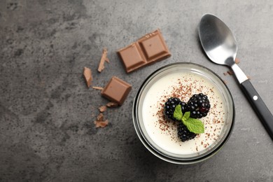 Photo of Tasty panna cotta with blackberries, mint and chocolate pieces on grey table, flat lay. Space for text
