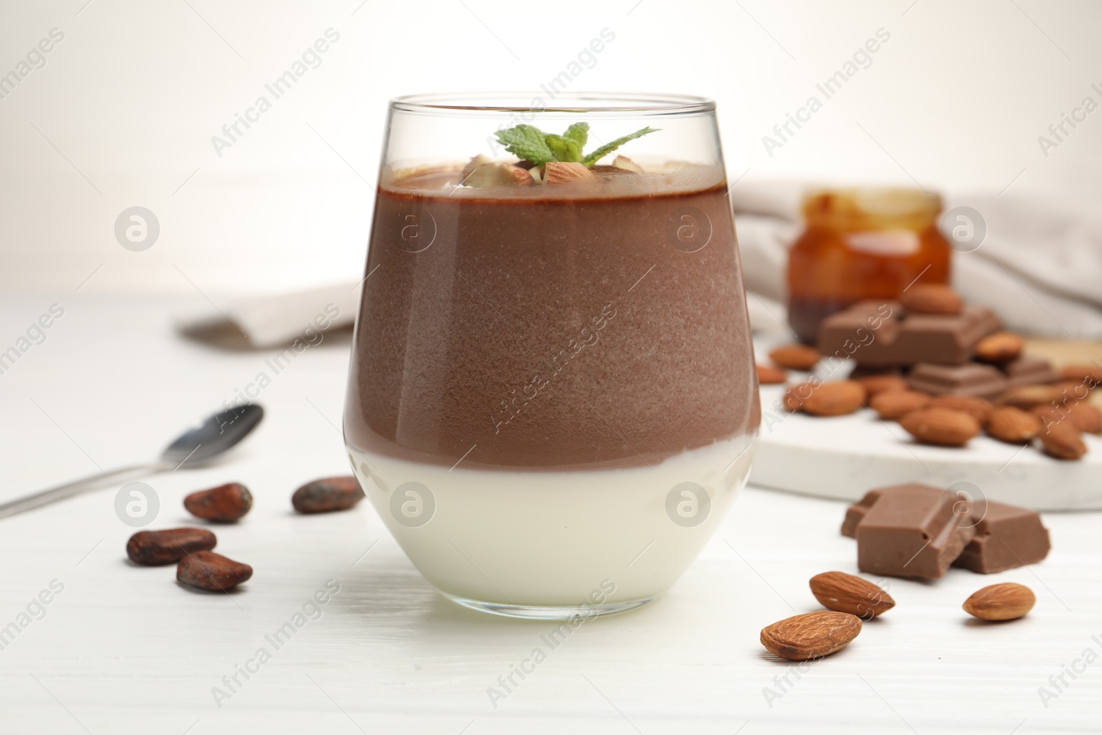 Delicious chocolate panna cotta with almonds, mint and cocoa beans on white wooden table, closeup Photo of Delicious chocolate panna cotta with almonds, mint and cocoa beans on white wooden table, closeup