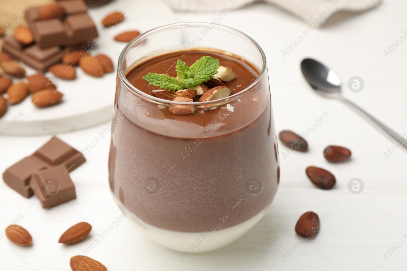 Delicious chocolate panna cotta with almonds, mint and cocoa beans on white wooden table, closeup Photo of Delicious chocolate panna cotta with almonds, mint and cocoa beans on white wooden table, closeup