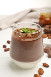 Photo of Delicious chocolate panna cotta with almonds and mint on white wooden table, closeup