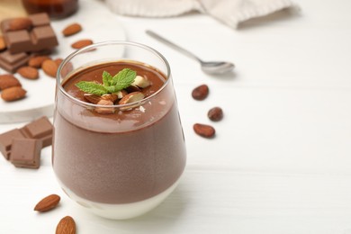 Photo of Delicious chocolate panna cotta with almonds and mint on white wooden table, closeup. Space for text