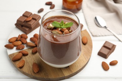Photo of Delicious chocolate panna cotta with almonds and mint on white wooden table, closeup