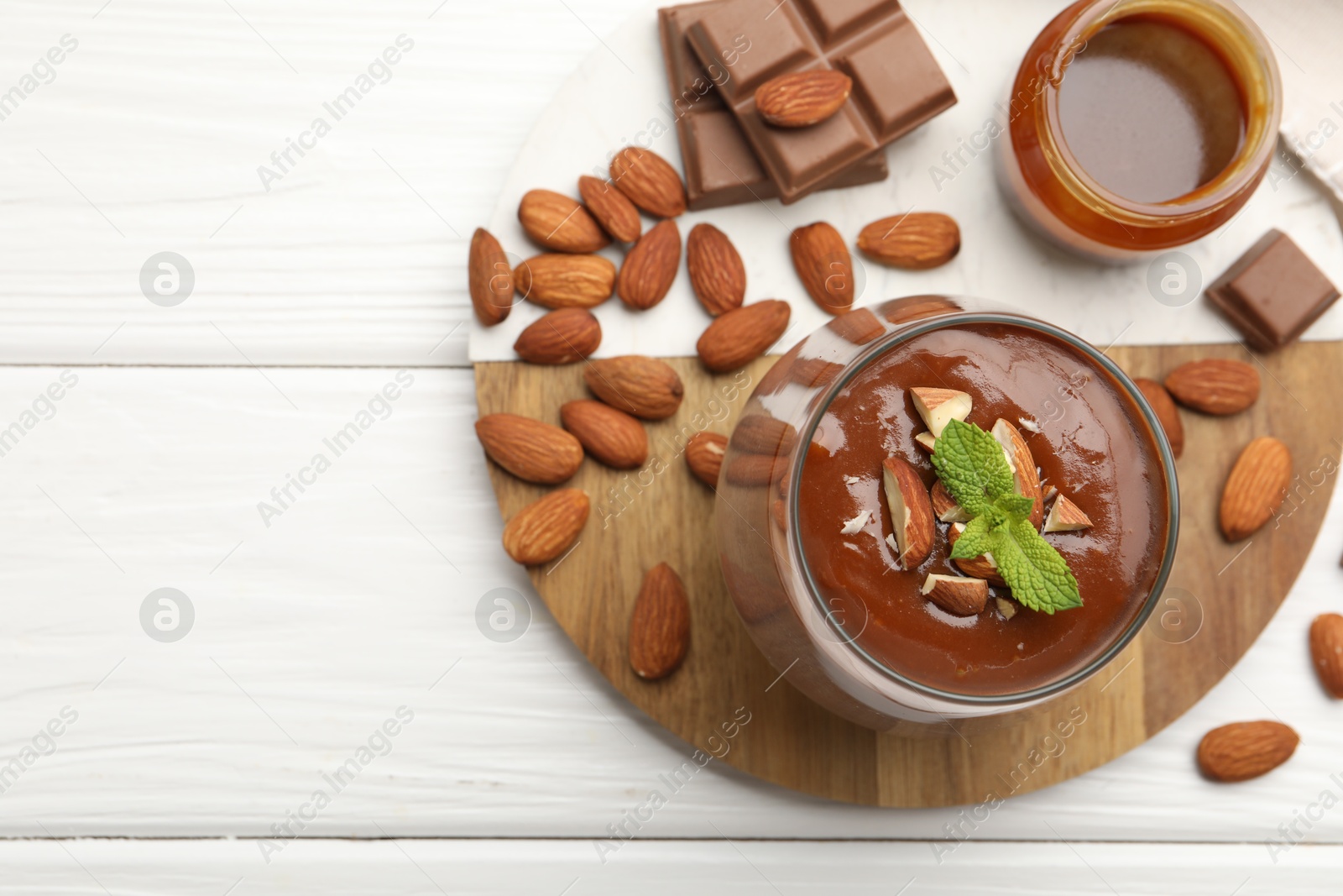 Delicious chocolate panna cotta with almonds, mint and caramel sauce on white wooden table, flat lay. Space for text Photo of Delicious chocolate panna cotta with almonds, mint and caramel sauce on white wooden table, flat lay. Space for text