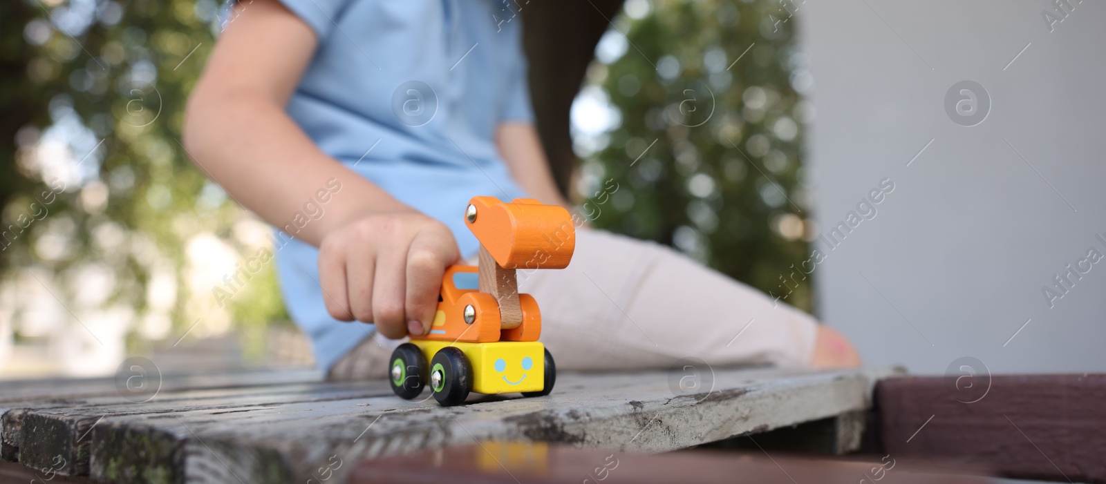 Little boy playing with toy car on wooden bench outdoors, closeup Photo of Little boy playing with toy car on wooden bench outdoors, closeup