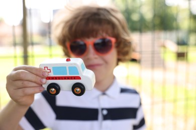 Photo of Little boy with toy car outdoors, selective focus