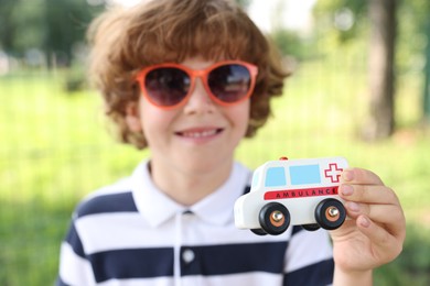 Photo of Little boy with toy car outdoors, selective focus