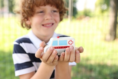 Photo of Little boy with toy car outdoors, selective focus