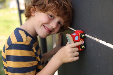 Photo of Little boy playing with toy car outdoors