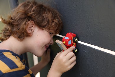 Photo of Little boy playing with toy car outdoors