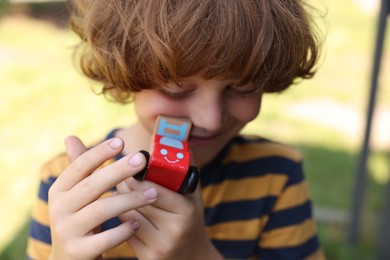 Photo of Little boy with toy car outdoors, closeup