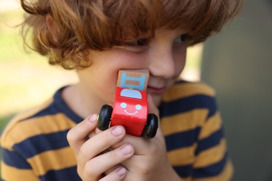 Photo of Little boy with toy car outdoors, closeup
