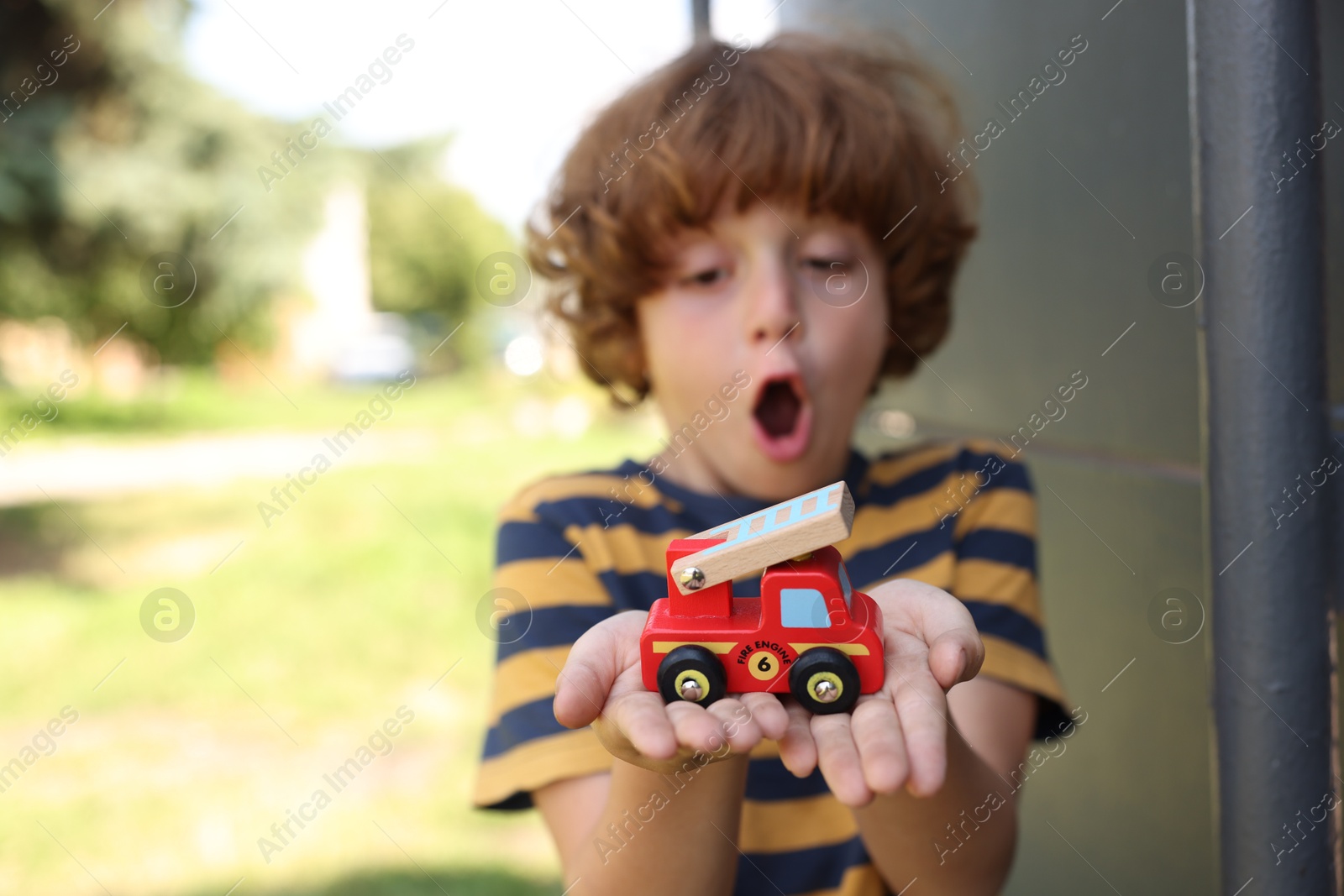 Surprised little boy with toy car outdoors, selective focus Photo of Surprised little boy with toy car outdoors, selective focus