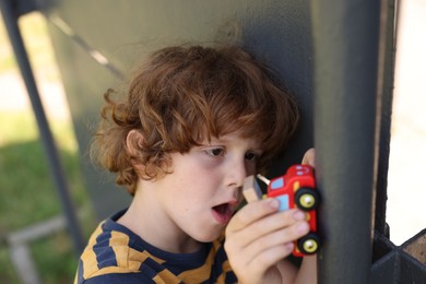 Photo of Little boy playing with toy car outdoors