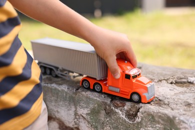 Photo of Little boy playing with toy car outdoors, closeup