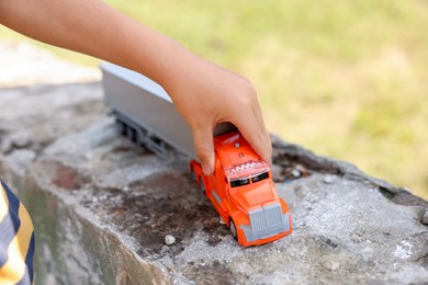 Photo of Little boy playing with toy car outdoors, closeup