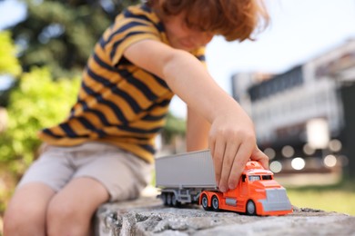 Photo of Little boy playing with toy car outdoors, selective focus