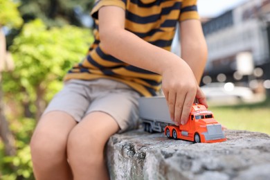 Photo of Little boy playing with toy car outdoors, closeup