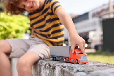 Photo of Little boy playing with toy car outdoors, selective focus