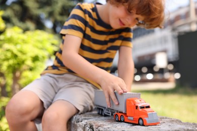Photo of Little boy playing with toy car outdoors, selective focus