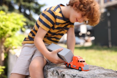 Photo of Little boy playing with toy car outdoors, selective focus