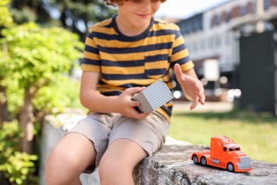 Photo of Little boy playing with toy car outdoors, selective focus