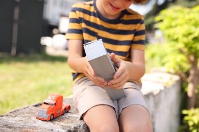 Photo of Little boy playing with toy car outdoors, closeup