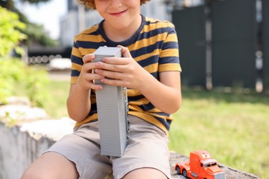 Photo of Little boy playing with toy car outdoors, closeup