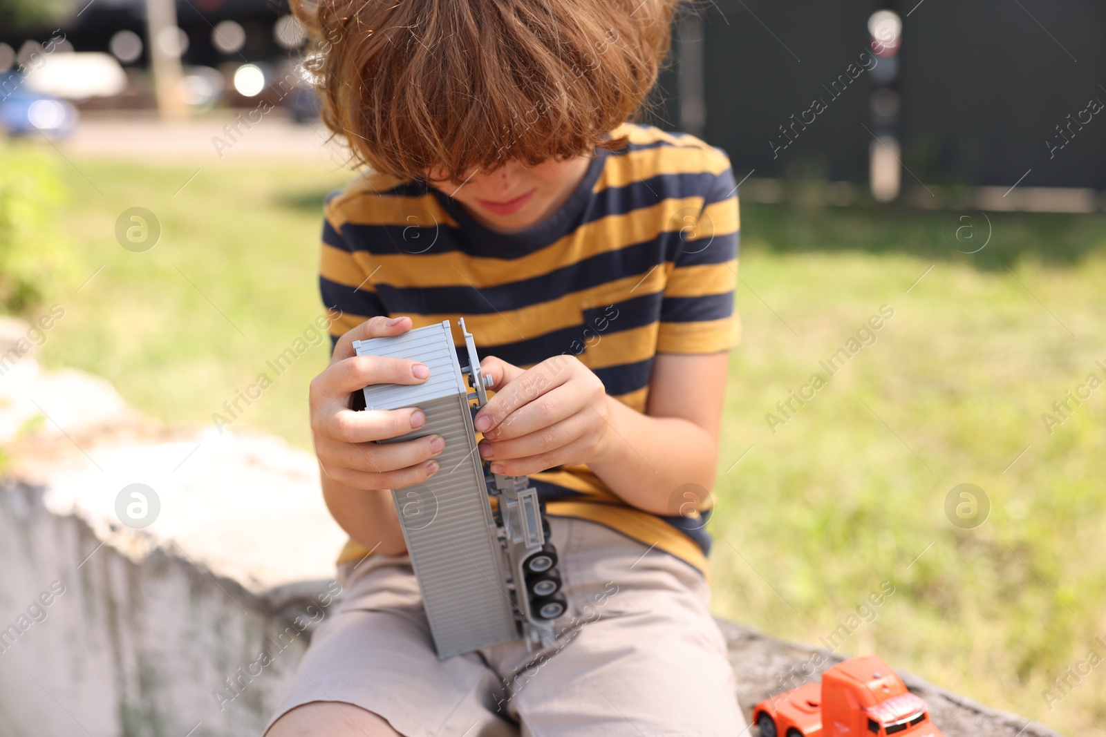 Little boy playing with toy car outdoors, selective focus Photo of Little boy playing with toy car outdoors, selective focus