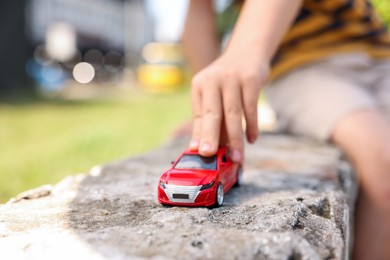 Photo of Little boy playing with toy car outdoors, closeup