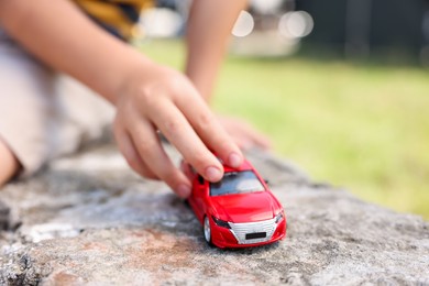 Photo of Little boy playing with toy car outdoors, closeup