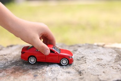 Photo of Little boy playing with toy car outdoors, closeup. Space for text