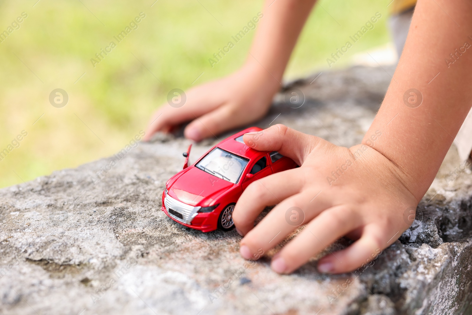 Little boy playing with toy car outdoors, closeup Photo of Little boy playing with toy car outdoors, closeup