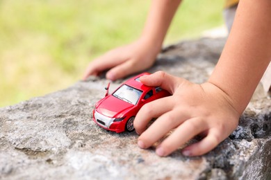 Photo of Little boy playing with toy car outdoors, closeup
